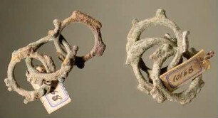 Zweimal je drei kleine miteinander verbundene Ringe mit hervorspringenden Verzierungen