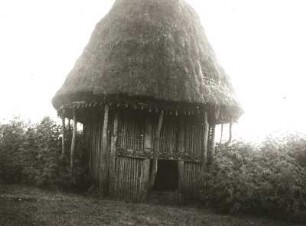 Banssu, Nordwest-Kamerun. Speicher aus hölzernem Gitterwerk mit geschnitztem Türsturz und pfeilergestütztem, grasgedecktem Kegeldach
