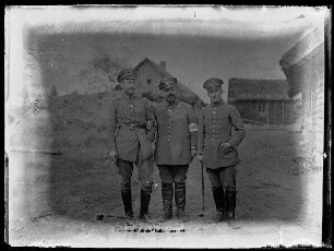 Unbekannte Ortschaft [Litauen/Weißrussland/Ukraine?]: Gruppenbild mit 3 Offizieren mit Schirmmütze, der mittlere mit einer Rot Kreuz-Armbinde