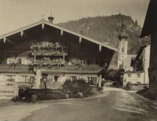 Reit am Winkl (Oberbayern). Typisches oberbayr. Bauernhaus. Im Hintergrund Pfarrkirche St. Pankratiuskirche