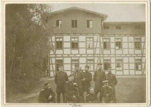 Gruppenbild vom Schiessplatz Lammsdorf, Offiziere (neun Personen), unter ihnen Max von Fabeck, General, vor Fachwerkgebäude (Kasino) teils stehend, teils sitzend oder kniend