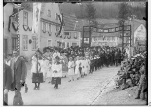 Primizfeier Heinzelmann in Stetten unter Holstein; Prozession durch einen geschmückten Torbogen; im Mittelpunkt Geistlichkeit