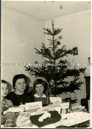 Mutter und Kinder mit Geschenken am Weihnachtsbaum