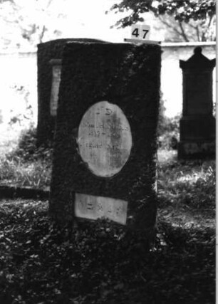 Grabstein 47 (Index: 100081706) Material: Granit, weiße Marmorplatte Zustand: gut Maße HxBxT: 147x65x27 cm Beschreibung: leicht konische Stele, gerader Abschluß, ovale und querrechteckige Schriftplatte: Grabstein 47