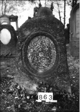 Grabstein 863 (Index: 99630365) Material: Granit Zustand: Platte fehlt Maße HxBxT: 110x70x50 cm Beschreibung: grob stelenhaft behauener Stein mit eingetieftem ovalem Schriftfeld: Grabstein 863