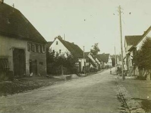 Genkingen (Schwäbische Alb). Wohnhäuser und Gehöfte einer Dorfstraße mit Kopfsteinpflaster und Rinnsteinen