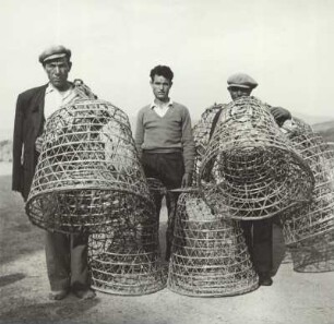 Bei Castelsardo. Sardinien. Fischer bringen die, aus Palmmaterial hergestellten leeren, Reusen zu ihren Booten