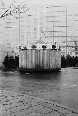 Abgedecktes Karussell vor Plattenbau