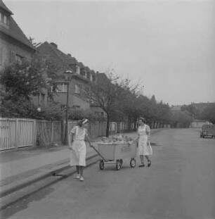 Zwei Kindergärtnerinnen mit einem Bollerwagen mit Kleinkinder