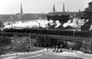 Hamburg. Ein Personenzug fährt Richtung Lombardsbrücke. Im Hintergrund die Silhouette der Altstadt mit ihren prägenden Türmen.