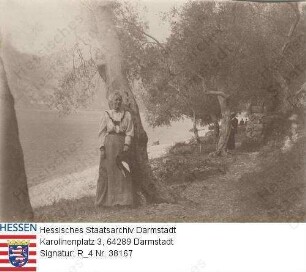 Tiedemann, Elisabeth v. geb. v. Werner (1868-1929) / Porträt, an Flußufer, an einen Baum gelehnt stehend, Ganzfigur