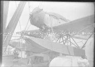 Junge Frau an Bord des Hochseepassagierdampfers "Bremen", auf dem abgedeckten und fixierten Katapultflugzeug HE 12 D-1717 posierend