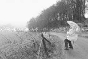 Person mit einem Regenschirm schaut durch ein Fernglas über die Landschaft (Sonderthema: Lebenskunst und Lebenskünstler)