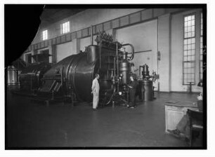 Industrie-Kraftwerk. Turbine, davor Werkstattschreiberin beim Protokollieren von Messwerten : Lauta (Niederlausitz). Industrie-Kraftwerk. Turbine, davor Werkstattschreiberin beim Protokollieren von Messwerten