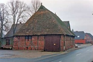 Havighorst: Dorfstraße 16: Hofanlage: traufständige Fachwerkscheune mit Reetdach und seitlicher Durchfahrt: Straßenfront: Giebelseite mit Scheunentor, Giebelzier: links rückwärtiger Anbau: dahinter Haupthaus