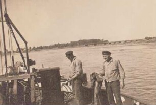 Schifferarbeiten, zwei Bootsleute an Deck eines Schiffes, einer streicht mit Teerfarbe