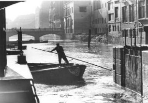 Hamburg. Ein Bootsmann bugsiert eine Schute durch das Alster-Fleet.