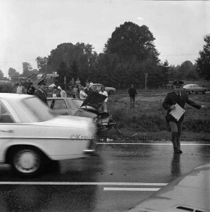 B 404: bei Nütschau: Verkehrsunfall: auf Kreuzung zwischen Travenberg und Nütschau: Zusammenstoß von zwei Pkws: beide Unfallwagen an den Straßenrändern: durchfahrender Pkw [bewegungsunscharf]: nasse Fahrbahn: zwei Polizisten auf Straße: dahinter Schaulustige: hinten Landstraße, Wegweiser, parkende Pkws, Traktor mit Güllefass
