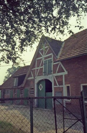 Langereihe 5: Bauernhaus: westliche Seitenfront: Wirtschaftstrakt mit Quergiebel, Scheunentor, Stalltüren: rechts Wohntrakt [angeschnitten]: im Vordergrund Zaun, Hofeinfahrt