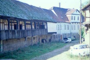 langgstreckter Innenhof des alten Gutes, hinten links Haupthaus, daneben Stall mit Laubengang, baufälliger Zustand