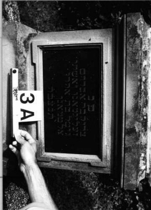 Grabstein 3 (Index: 99802002) Material: Sandstein, zwei schwarze Schriftplatte Zustand: Schriftplatte der Stele gesprungen Maße HxBxT: 195x60x27 cm Beschreibung: Stele, getreppter Sockel, eingezogener Rundbogenabschluß mit Mittelakroter, eingetiefte Schriftplatte rechteckig Symbolik: Blüte, Fries Besonderheit: Doppelgrab für Eheleute: Grabstein 3A