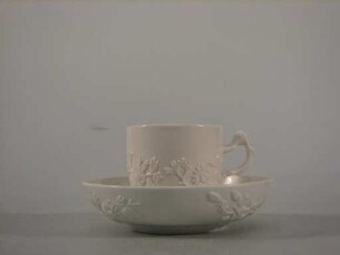 Teetasse und Untertasse mit reliefierten Blütenstauden