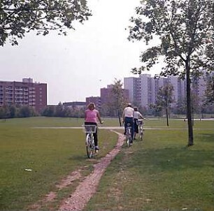 Hansjakob, Gottfried; München - Neuperlach Mitte; Wohnring Neuperlach - Innenraum Wohnring, Freifläche, Aufnahme mit Fahrradfahrern, im Hintergrund Wohnbauten