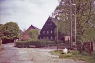 Fritz-Berodt-Straße: rechts Bauernhaus, Giebelseite Wohntrakt mit Kletterpflanzen, Giebelzier: links dahinter Hofanlage Nr. 7-9, östliches Wirtschaftsgebäude, Giebel mit Verbretterung, Giebelzier: Bildrand links Hofeinfahrt