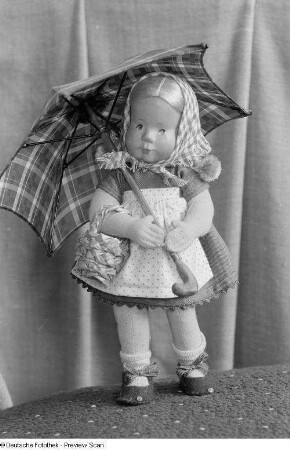 Eine Puppe (vermutlich von Ursel Erbs) mit Regenschirm, Kopf aus Holz