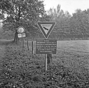 Nienwohlder Moor: Naturschutzgebiet: Hinweisschild: links Straßenschild: rechts Moorwiese: im Hintergrund Bäume und Sträucher