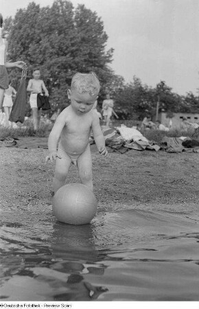 Kleiner Junge, mit einem Ball am Ufer spielend