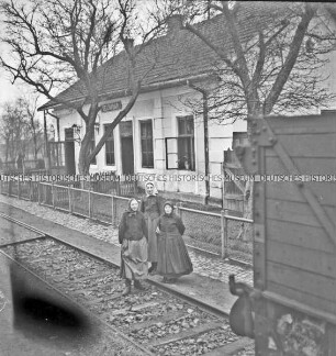 Drei Frauen vor dem Bahnhof von Selimbar, aus einem fahrenden Zug fotografiert
