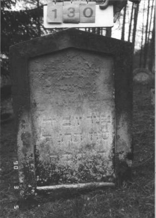 Grabstein 130 (Index: 99608814) Material: Sandstein Zustand: stark verwittert mit Textverlust Maße HxBxT: 90x60x13 cm Beschreibung: Stele mit Spitzgiebel, vertiefter Textteil in gleicher Form: Grabstein 130