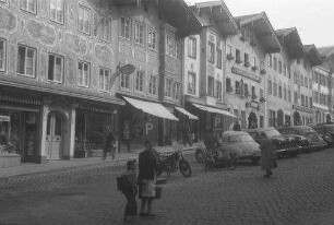 Bad Tölz: Hauptstraße [Marktstraße] mit Parkplatz und Brunnen [Schulkind mit Schultüte]