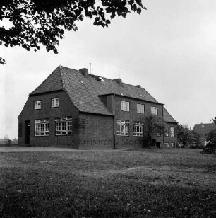 Volksschule: rechts davor Bäume: vorn Rasen