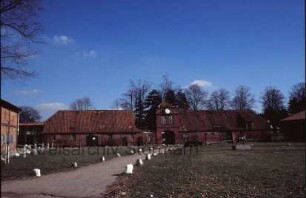 Gut Tangstedt: Torhaus: Hofseite: Durchfahrt, in Giebel Uhr: links Nordflügel, Dach eingestürzt: rechts Südflügel: davor Bauzaun: am Bildrand Nebengebäude: vorne Weg, Wiese, Pferdeskulptur