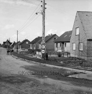 Alte Dorfstraße: Kreisstraße nach Rethwischdorf mit Neubausiedlung: rechts Einfamilienhäuser: in der Mitte Strommast: hinten links Mädchen und Kind mit Kinderwagen