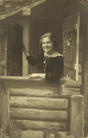 [Eine junge Frau schaut aus einem Stallfenster heraus]