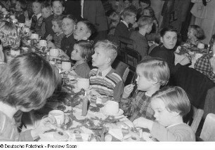 Kinder an einer gedeckten und geschmückten Tafel bei der Weihnachtsfeier des Verlags Volk und Wissen