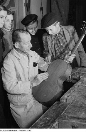Gitarrenbauer beim Polieren des Instrumentes umringt von Gästen auf der Weihnachtsausstellung im Alten Rathaus "Klingendes Vogtland"