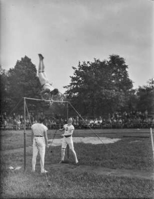 Dresden. Schüler bei einer Übung am Reck auf einem Sportplatz mit Zuschauern
