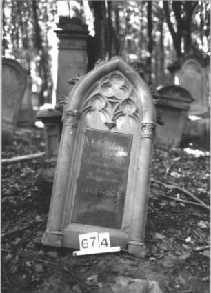 Grabstein 674 (Index: 99900551) Material: Sandstein, Granit?tafel Zustand: gut erhalten, Stele vom Sockel gestürzt Maße HxBxT: 190x52x22 cm Beschreibung: ursprünglich aufgesockelte Stele mit Spitzbogenabschluss, Oberrahmen mit Krabben besetzt, im Bogenfeld Maßwerk, die Schriftfelder flankiert von Säulen, vom Sockel gestürzt lehnt an diesem: Grabstein 674