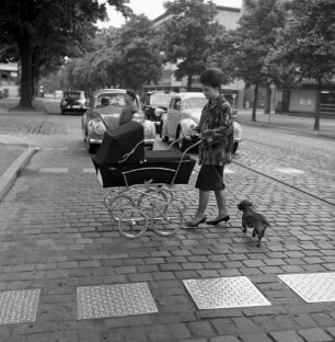 Frau mit Kinderwagen beim Überqueren einer Straße