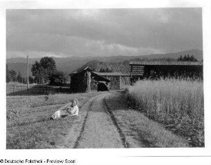 Slowenien. Feldscheune vor Bergkulisse. Ansicht mit Reisebegleiterin der Fotografin