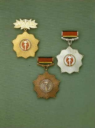 Vaterländischer Verdienstorden : Auszeichnung der Deutschen Demokratischen Republik. Vaterländischer Verdienstorden in Gold, Silber und Bronze mit Spange bzw. Ehrenspange (zum Orden in Gold). Buntmetall, vergoldet, versilbert bzw. bronzefarben, geschraubt (Spange); Durchmesser 5,3 cm. Gestiftet am 21.4.1954. Silber und Bronze in der 1. Ausführung