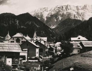 Wolkenstein in Gröden. Südtirol. Italien. Panorama des Ortes. Links die um 1880 im Stil des Spätbarocks erbaute St. Sylvester-Kapelle. Im Hintergrund das Bergmassiv der Sellagruppe
