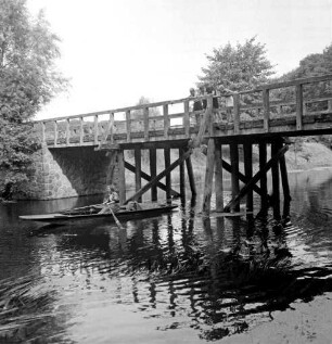 Trave: darüber Friedensbrücke: rechts oben Kinder am Geländer: links Frau in Ruderboot: hinten Bäume