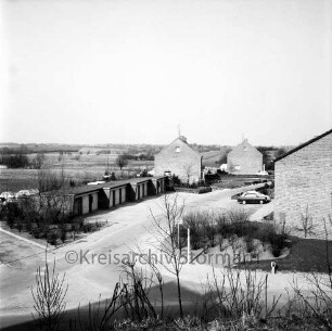 Memeler Straße: Wohngebäude, links Garagen, vorne Königsberger Straße, im Hintergrund Feldmark: Blick nach Nordwesten