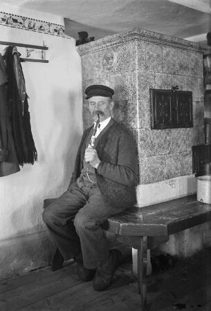 Portrait eines älteren Mannes, auf einer Ofenbank sitzend