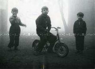 Drei Jungen im Nebel, einer auf einem Fahrrad